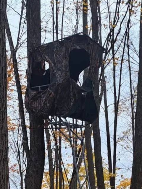Hunter setting up a tree stand blind in forest showing camouflage concealment setup guide